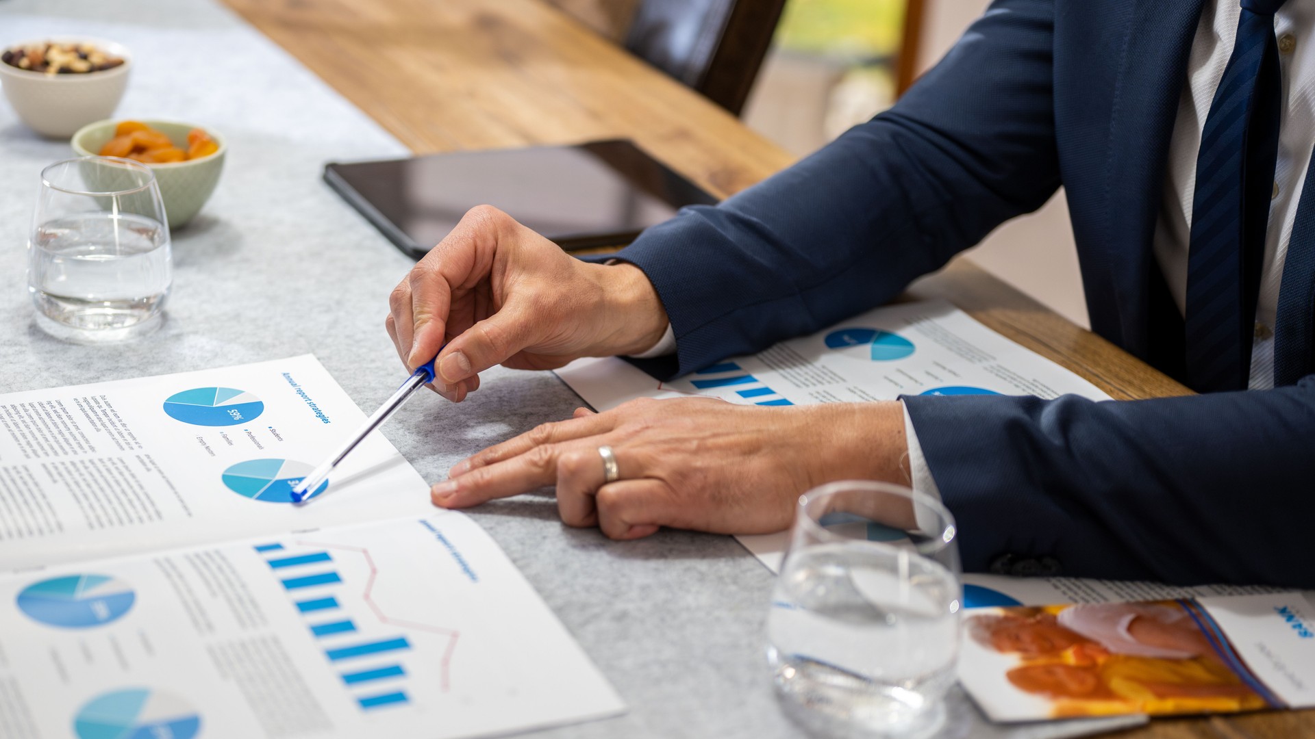 Male hands pointing with pen at charts on documents